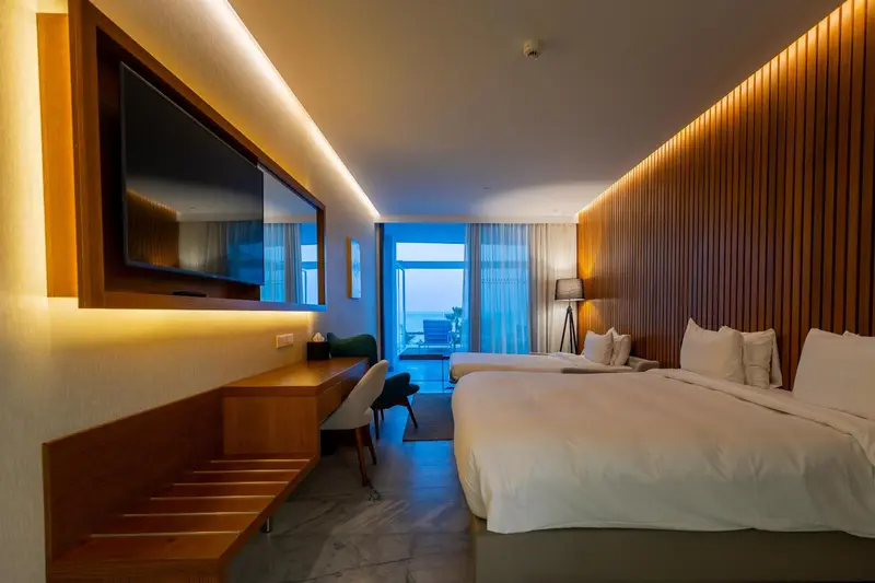 Chambre lumineuse avec deux lits et vue sur l'extérieur.