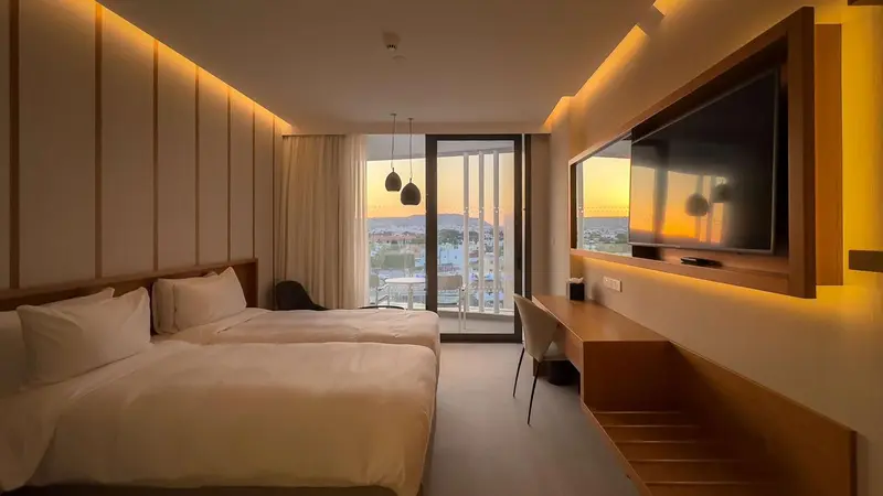 Chambre lumineuse avec un grand lit et une vue sur le paysage.