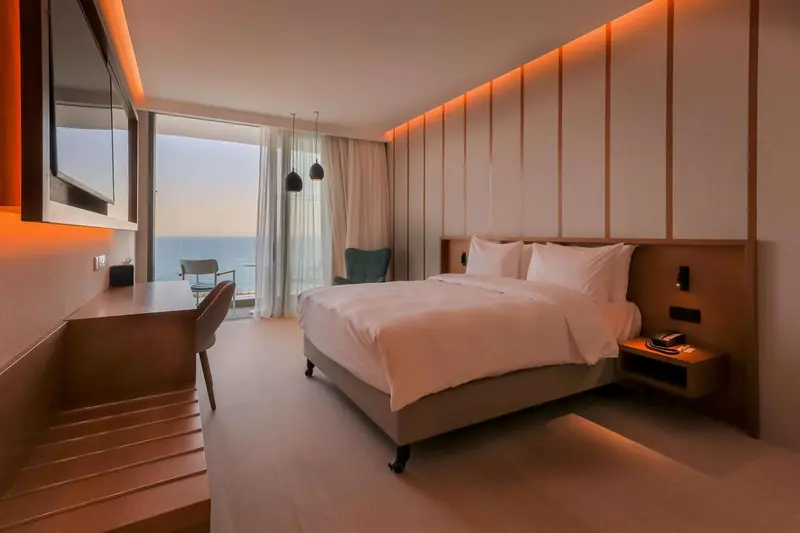 Chambre lumineuse avec un grand lit et vue sur la mer.