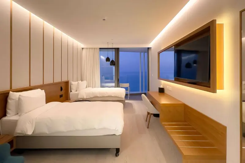 Chambre lumineuse avec lits jumeaux et vue sur la mer.