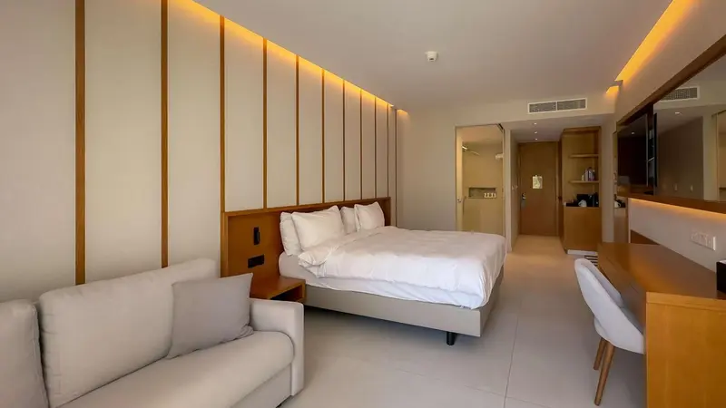 Une chambre lumineuse avec un lit double et un coin salon.