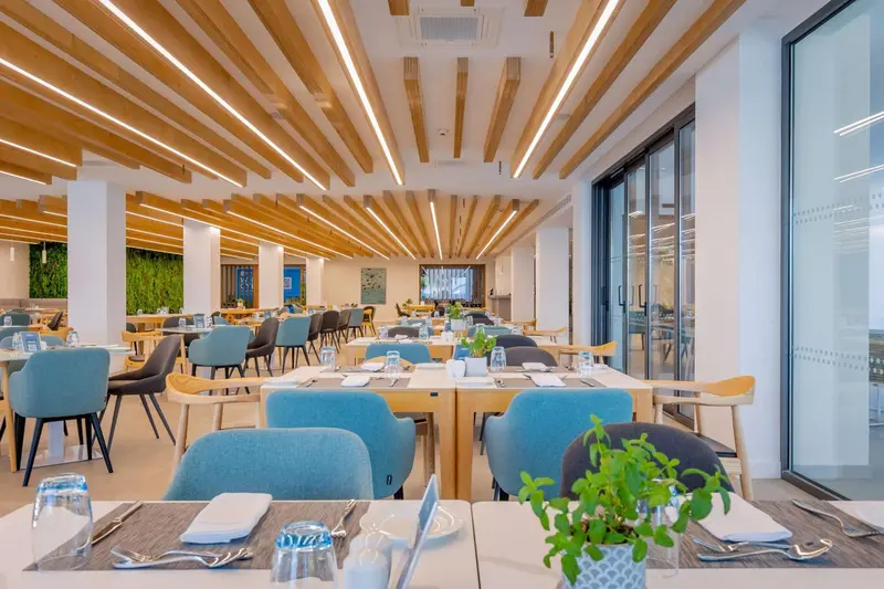 Une salle lumineuse avec des tables dressées pour un repas.