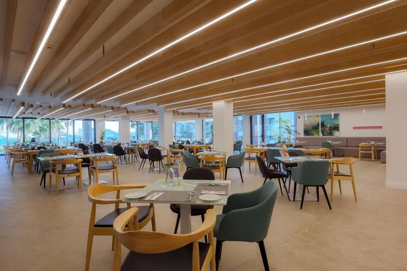 Une salle lumineuse avec des tables dressées pour un repas.