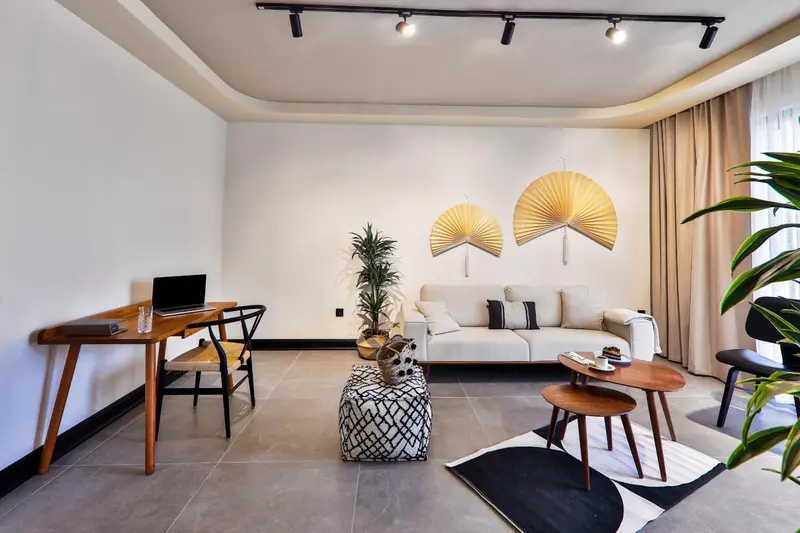 Espace de vie intérieur lumineux avec canapé, table basse et bureau.