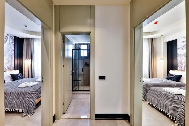 Intérieur clair avec deux lits jumeaux reflétés dans des miroirs.