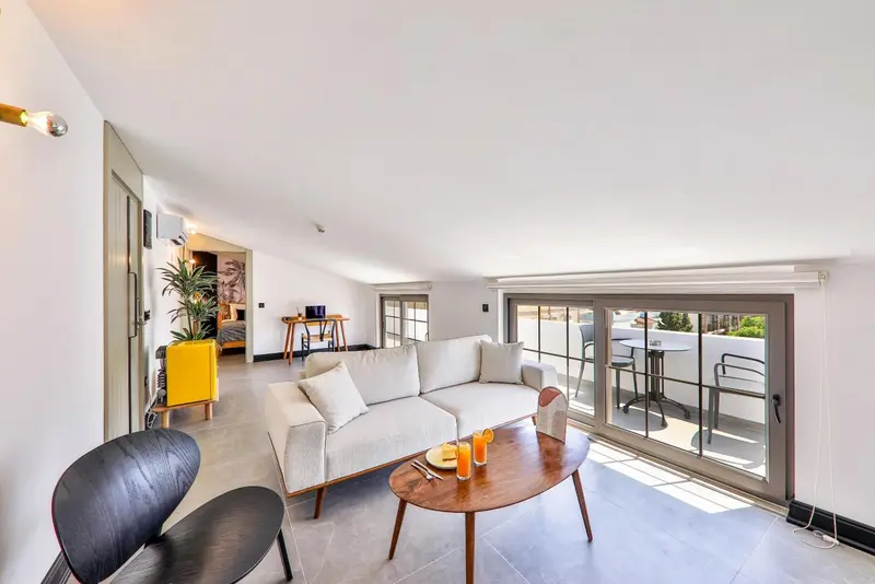 Espace de détente lumineux avec canapé et accès à une terrasse.