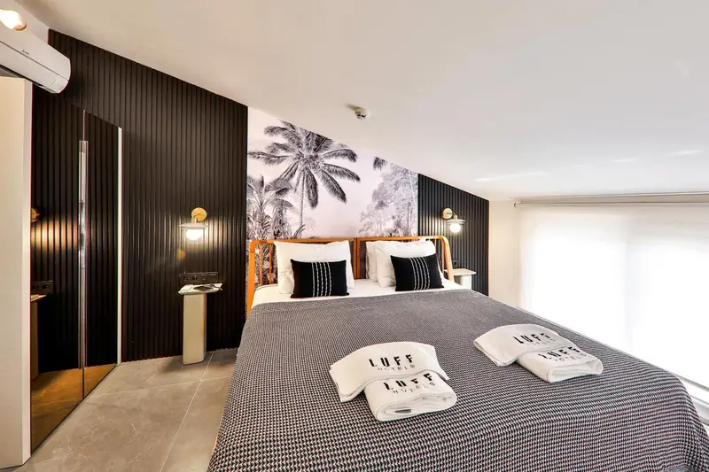Une chambre moderne avec un grand lit et une décoration murale tropicale.