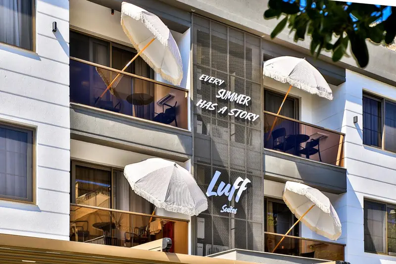 Facade d'un bâtiment avec des parasols blancs sur les balcons.