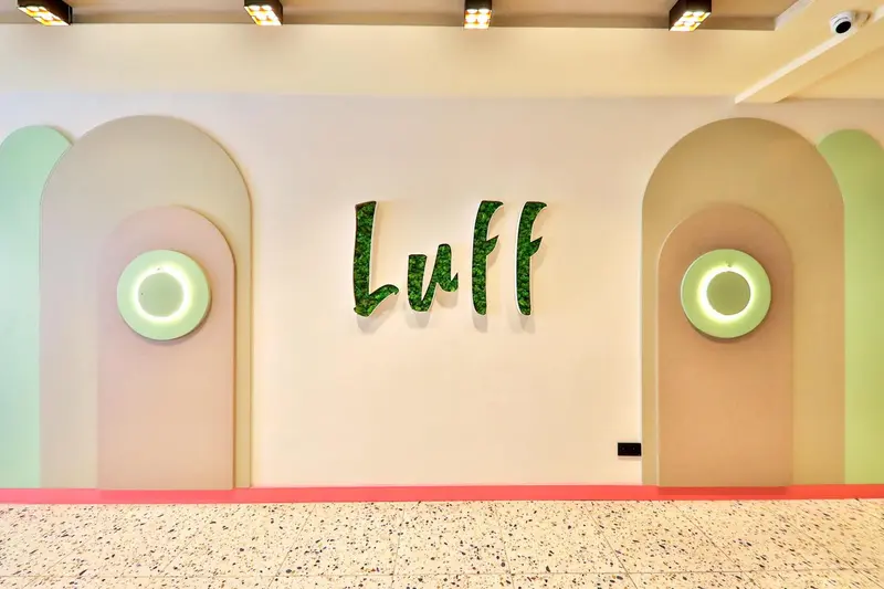 Décoration murale avec le mot "Luff" en lettres vertes et des cercles lumineux.