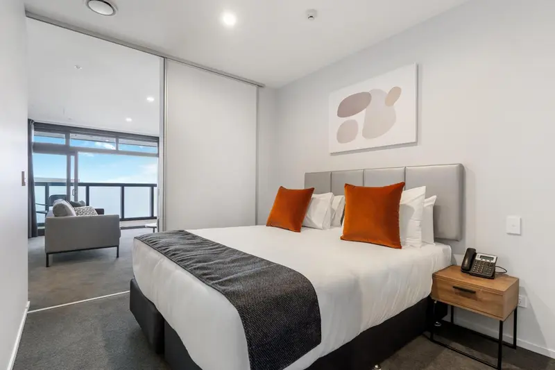 Une chambre moderne avec un grand lit et un canapé près d'une fenêtre.