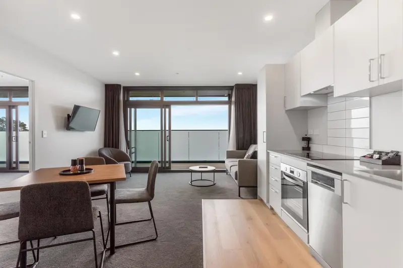 Espace de vie lumineux avec cuisine équipée et accès à un balcon.