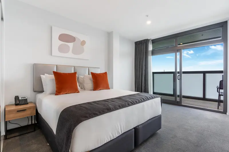 Une chambre moderne avec un grand lit et un accès à un balcon.