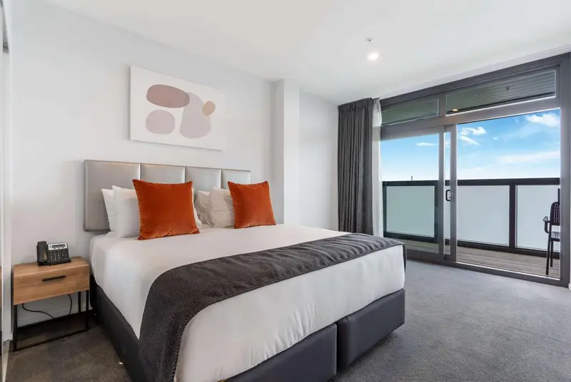 Une chambre moderne avec un grand lit et un accès à un balcon.