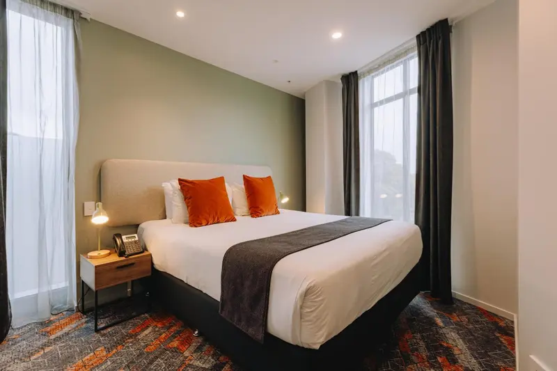 Une chambre lumineuse avec un grand lit et des oreillers orange.