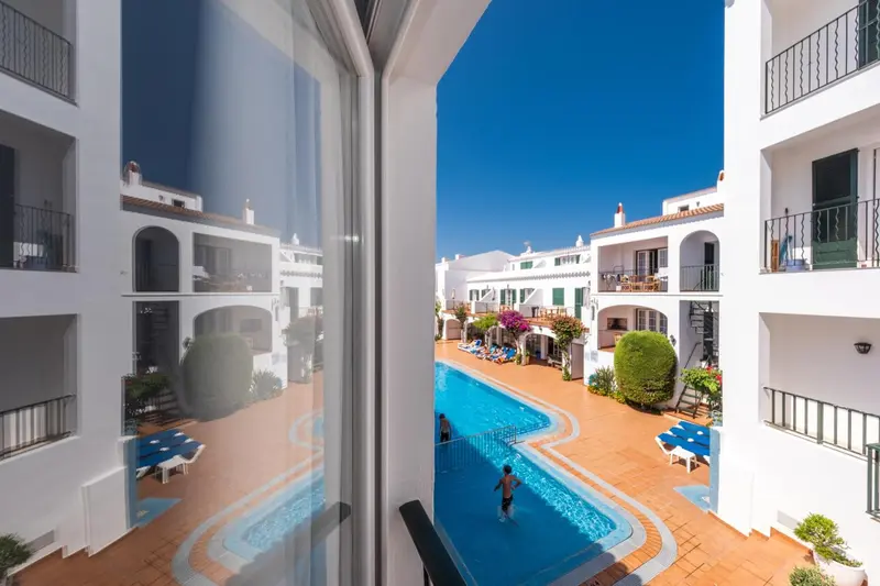 Vue sur une piscine depuis un balcon ensoleillé.