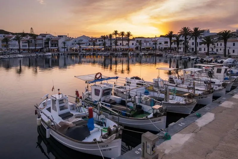 Port de plaisance au coucher du soleil avec des bateaux amarrés.