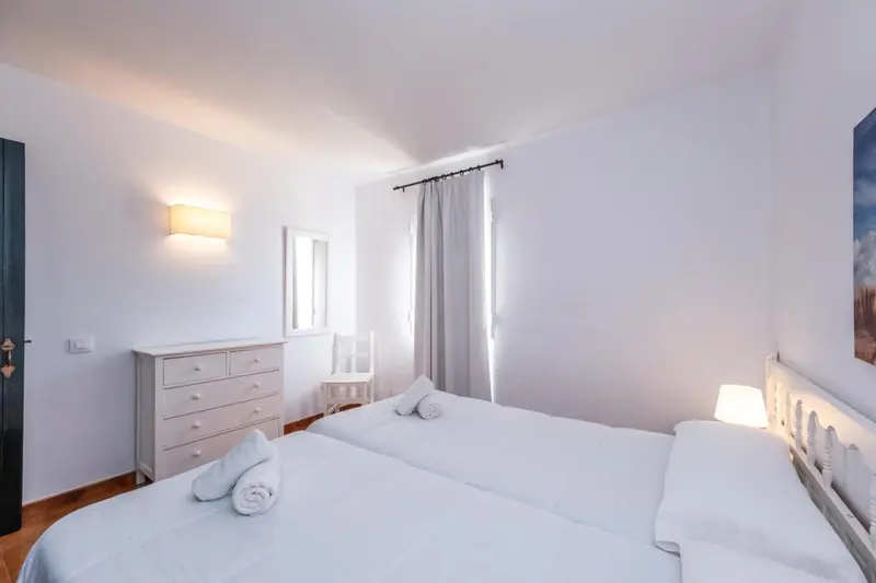 Une chambre lumineuse avec un lit double et une commode.