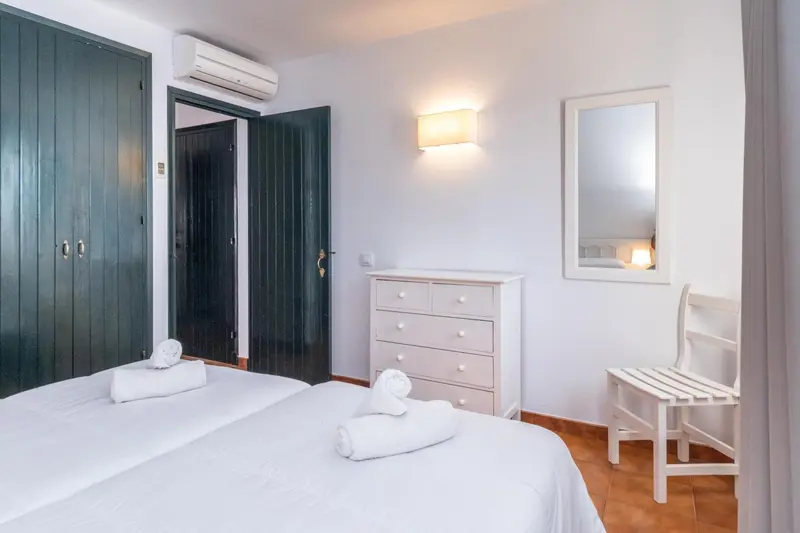Une chambre lumineuse avec deux lits simples et une commode.