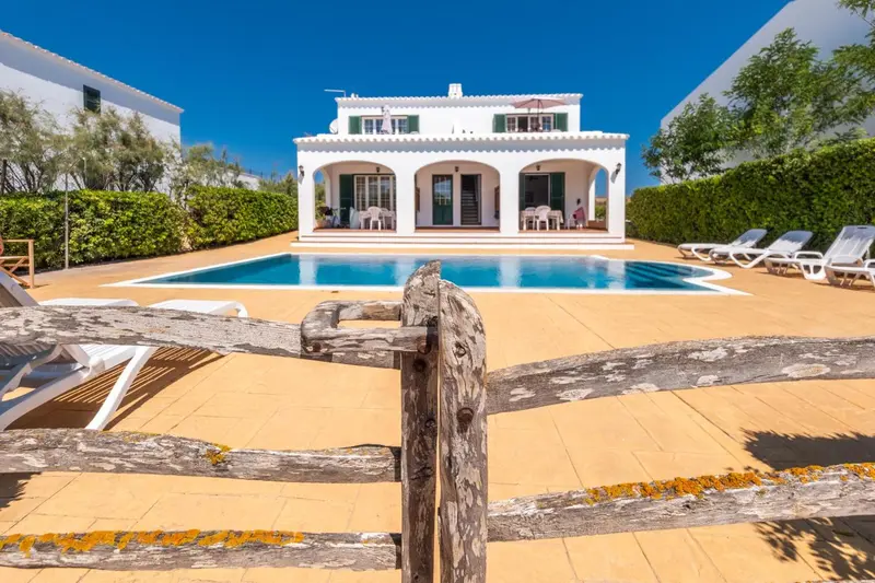 Villa blanche avec piscine et terrasse ensoleillée.