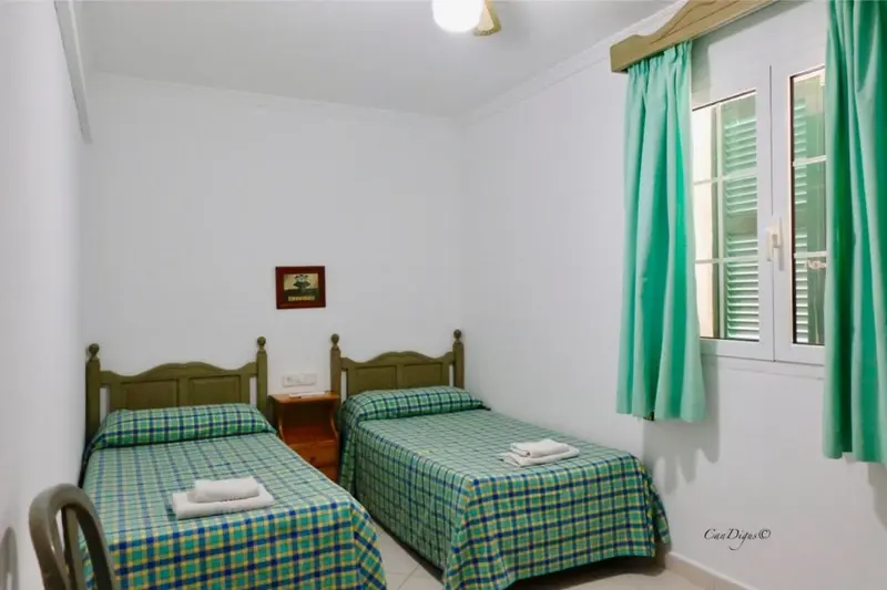 Une chambre lumineuse avec deux lits simples et une fenêtre.