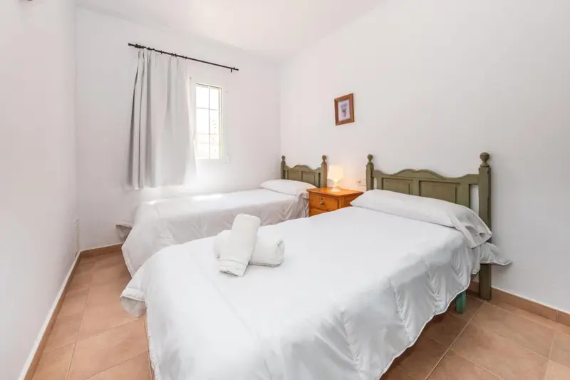 Une chambre lumineuse avec deux lits simples et une fenêtre.