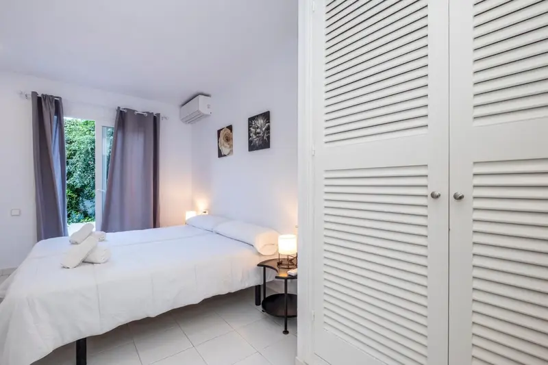 Une chambre lumineuse avec un lit blanc et des rideaux gris.