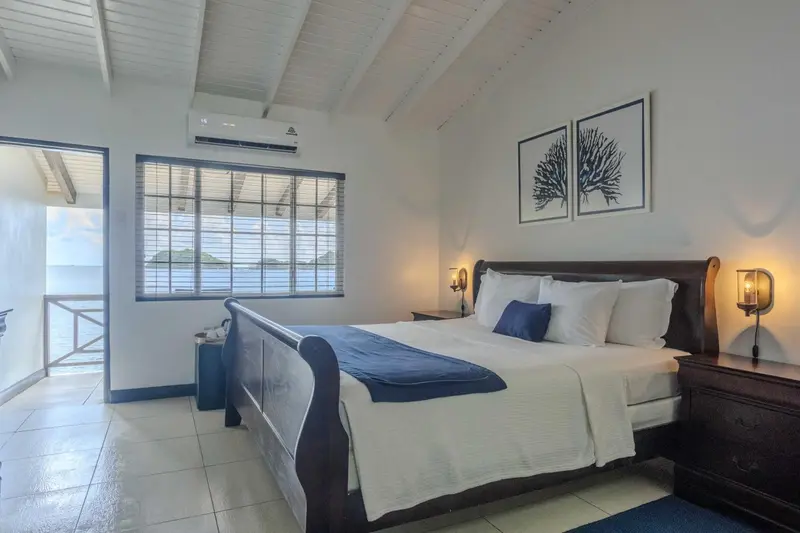 Chambre lumineuse avec un grand lit et vue sur la mer.