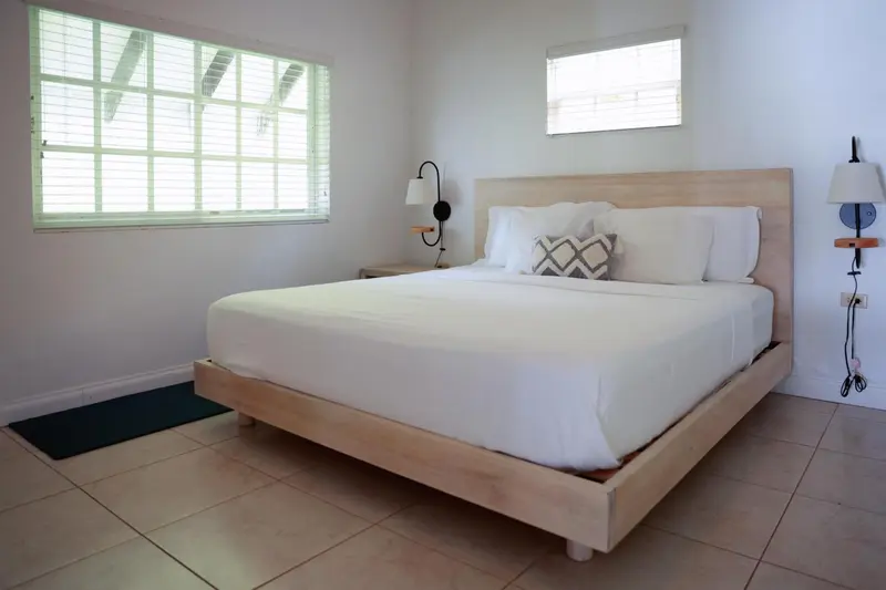 Une chambre lumineuse avec un grand lit recouvert de blanc.