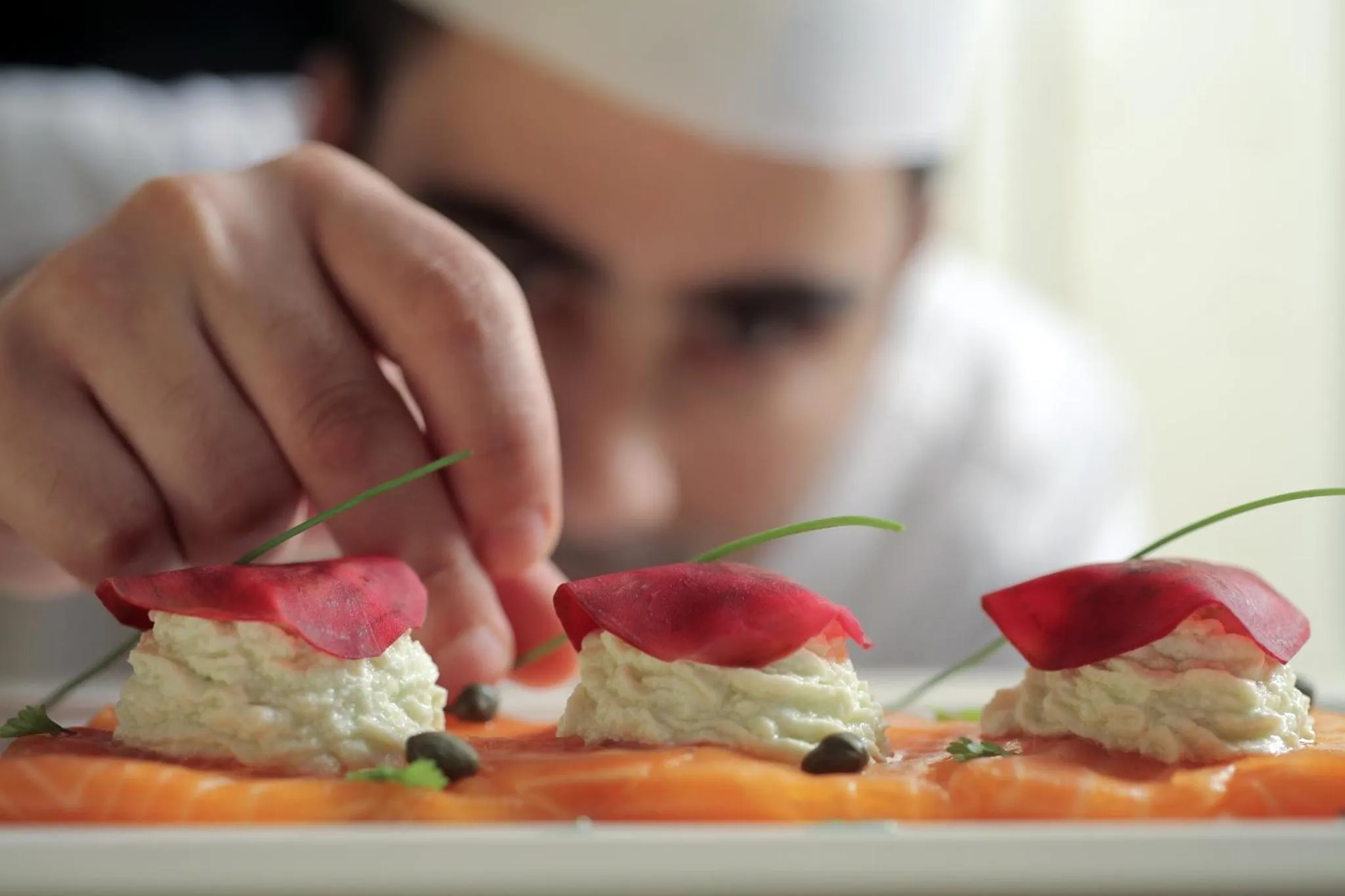 Un chef décore une assiette de hors-d'œuvre raffinés.