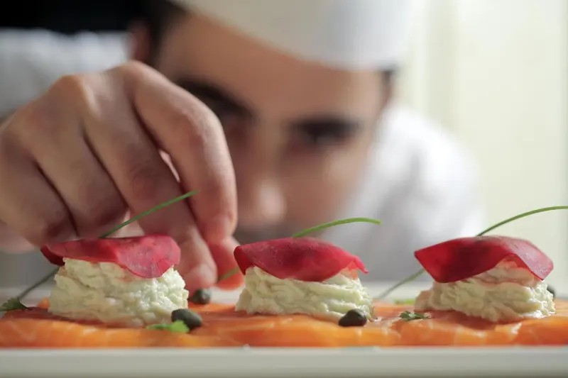 Un chef décore une assiette de hors-d'œuvre raffinés.