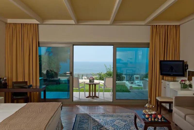 Chambre lumineuse avec vue sur la mer et accès à une terrasse.