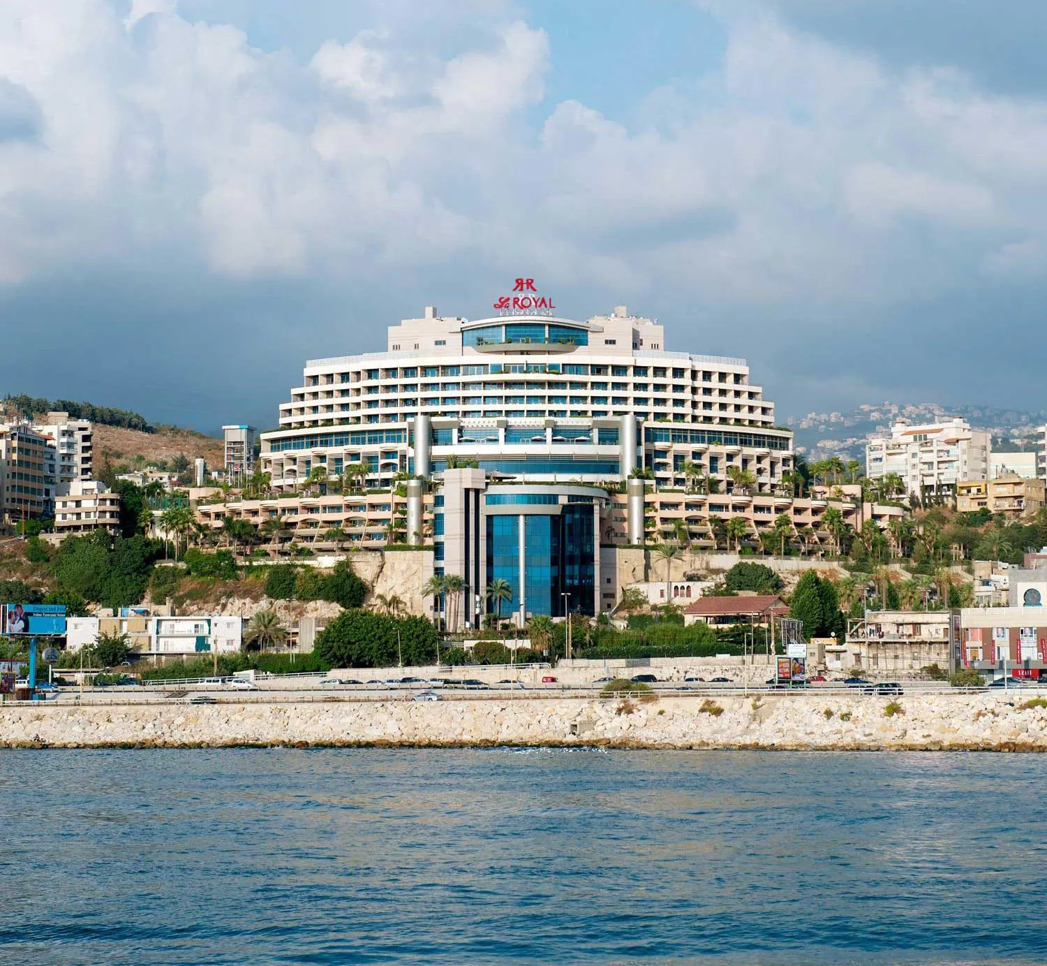 Vue d'un grand hôtel blanc avec de nombreuses terrasses surplombant la mer.
