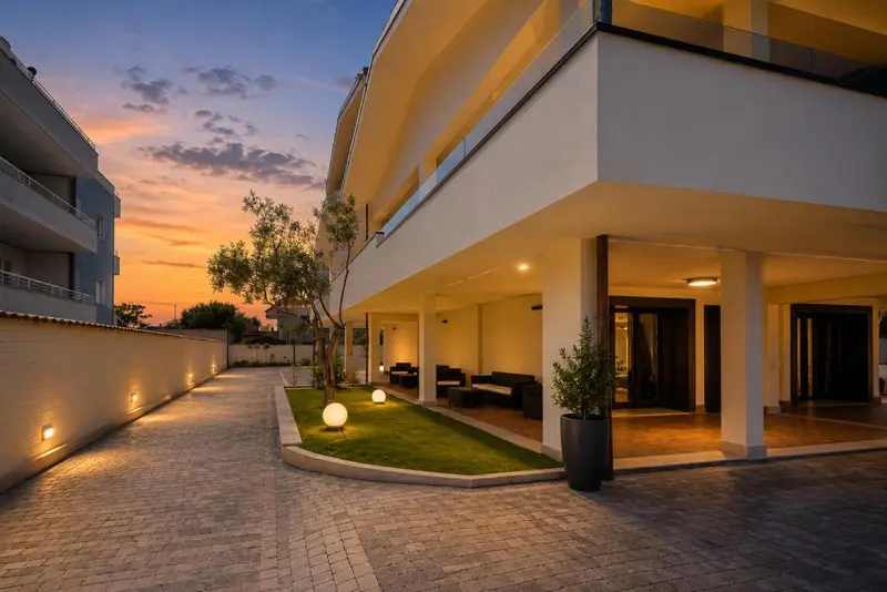 Facade d'un bâtiment moderne avec un jardin éclairé au crépuscule.
