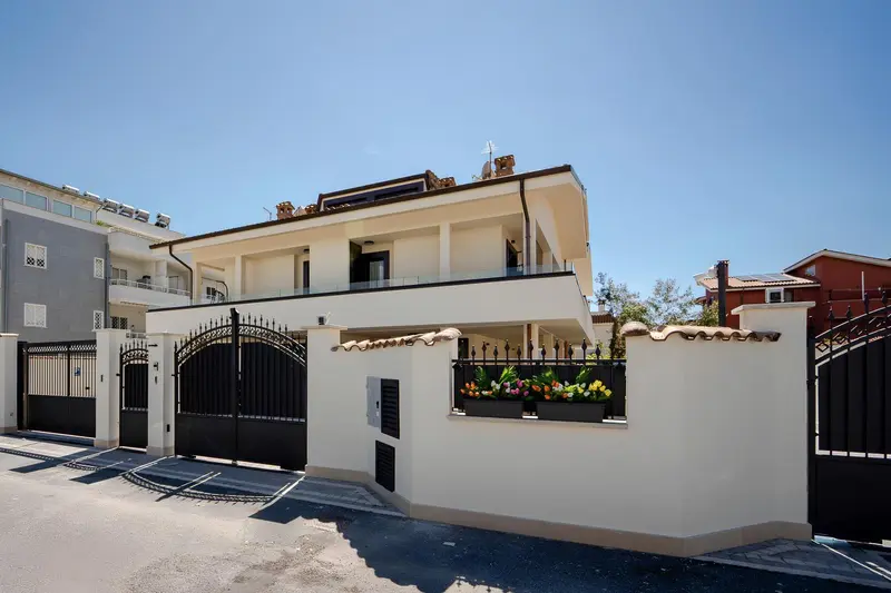 Façade d'un bâtiment blanc avec une grille en fer forgé et des fleurs colorées.