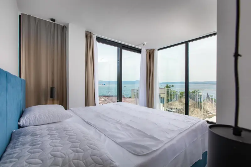 Une chambre lumineuse avec un grand lit donnant sur une vue mer.