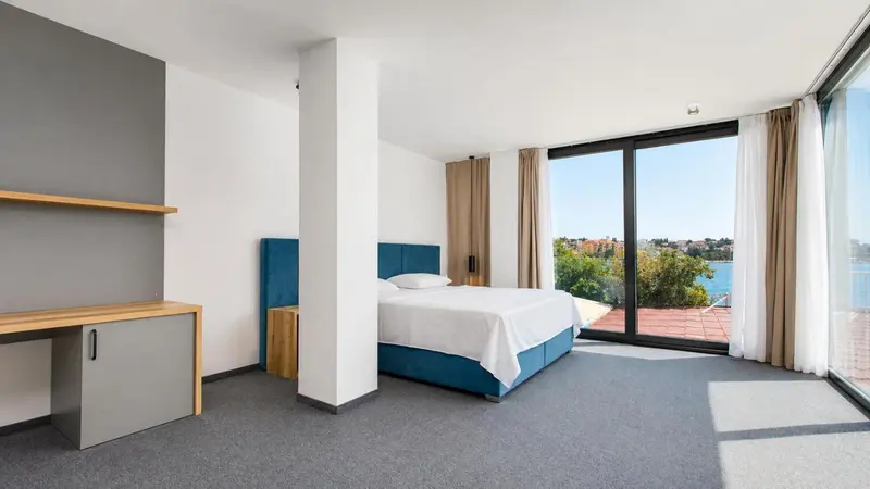 Chambre lumineuse avec un grand lit et une vue sur la mer.
