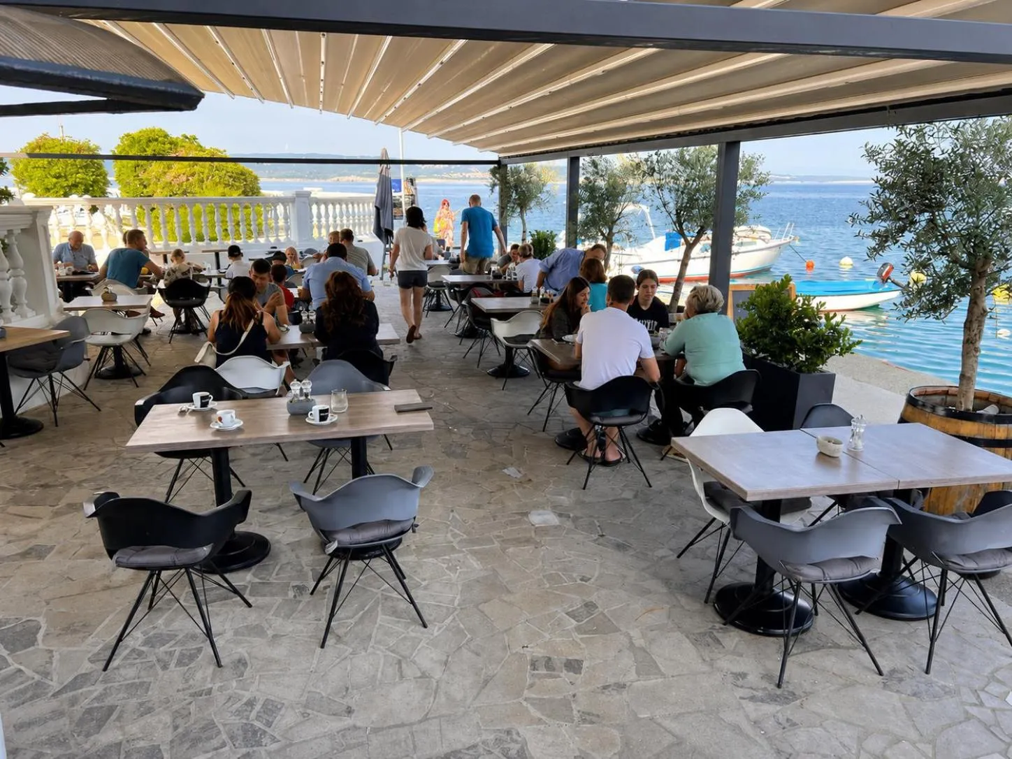 Une terrasse ombragée avec des tables et des chaises accueillant des clients.