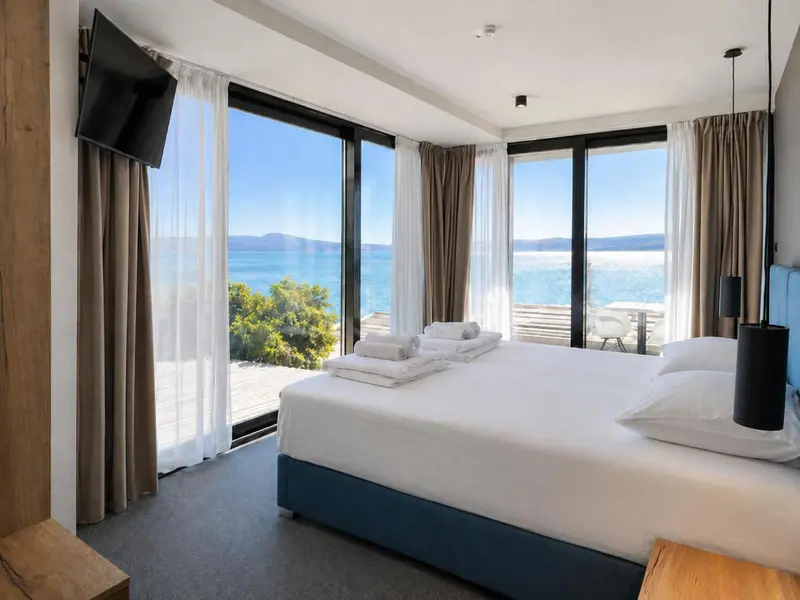 Une chambre lumineuse avec un grand lit donnant sur la mer.