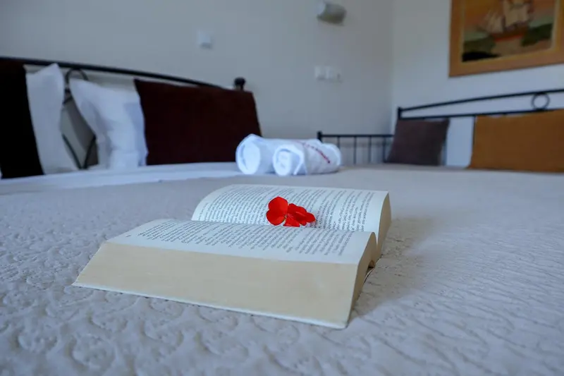 Un lit soigneusement fait avec un livre ouvert et des serviettes roulées.