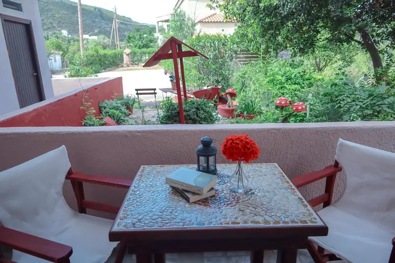 Une table et des chaises se trouvent sur une terrasse fleurie.