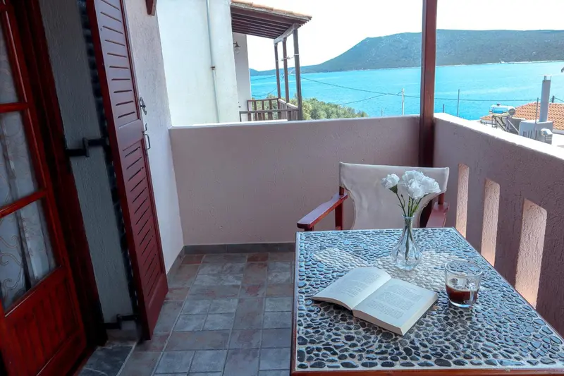 Une terrasse avec une table et des chaises offre une vue sur la mer.