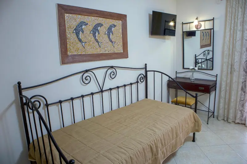 Une chambre avec un lit en fer forgé et une décoration murale.