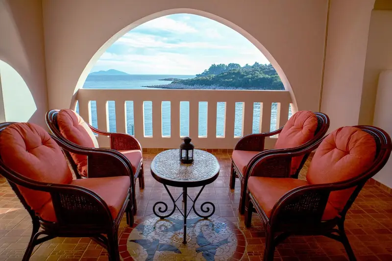Deux fauteuils et une table basse sur une terrasse avec vue sur la mer.
