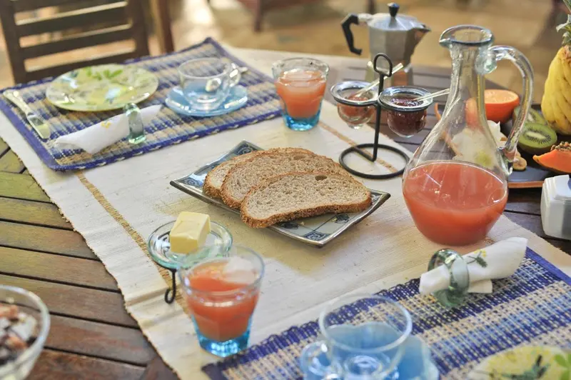 Une table est dressée pour le petit-déjeuner avec des fruits, du pain et des boissons.