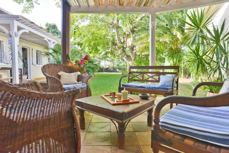 Espace extérieur aménagé avec des fauteuils en osier et une table basse.