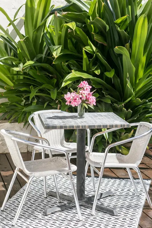 Une table ronde et des chaises en métal sur une terrasse carrelée.