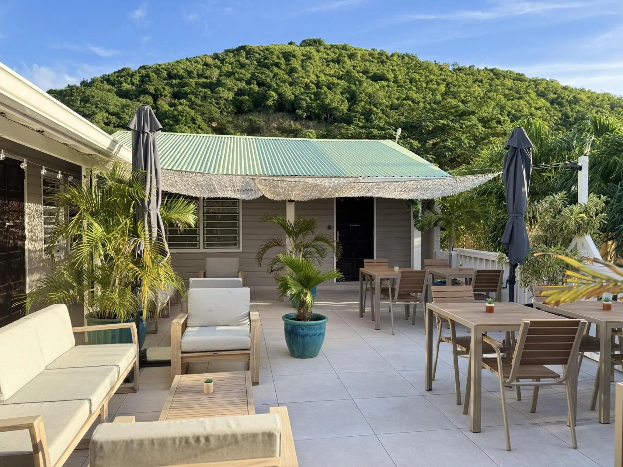 Terrasse ombragée avec mobilier de jardin et végétation luxuriante.