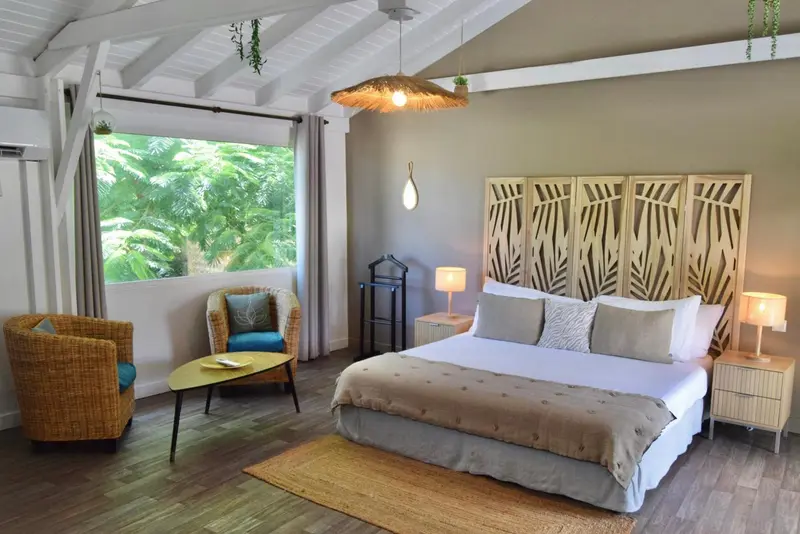 Une chambre lumineuse avec un lit double et un coin salon.