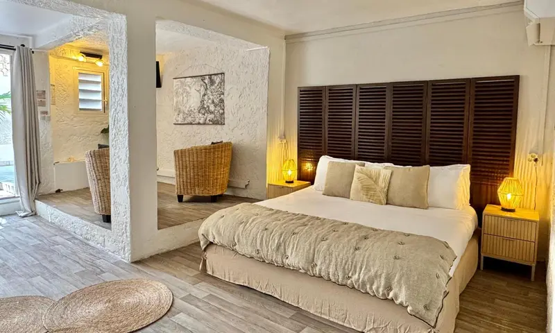 Une chambre lumineuse avec un grand lit et un coin salon.