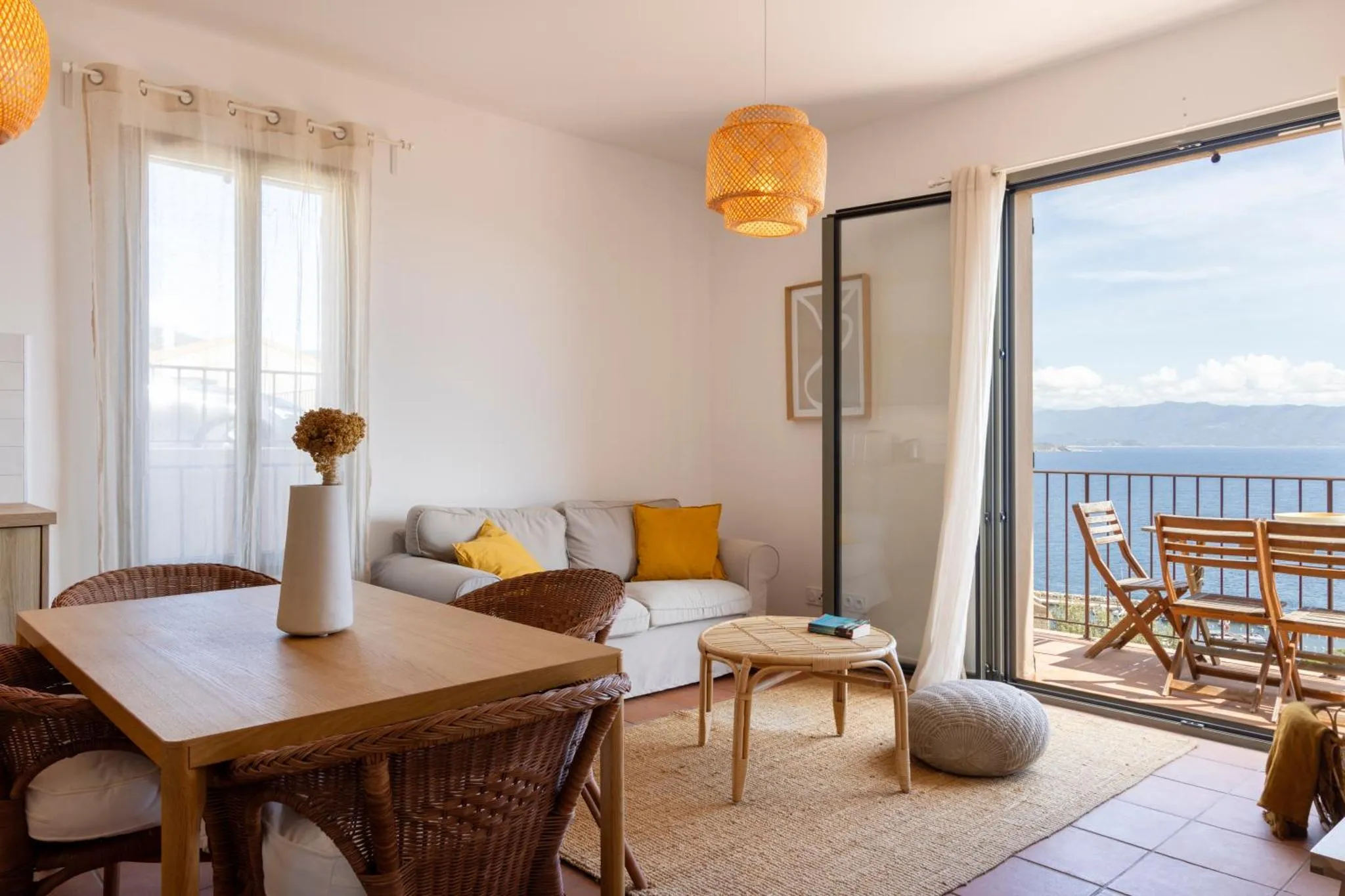Une pièce de séjour lumineuse s'ouvre sur une terrasse avec vue sur la mer.
